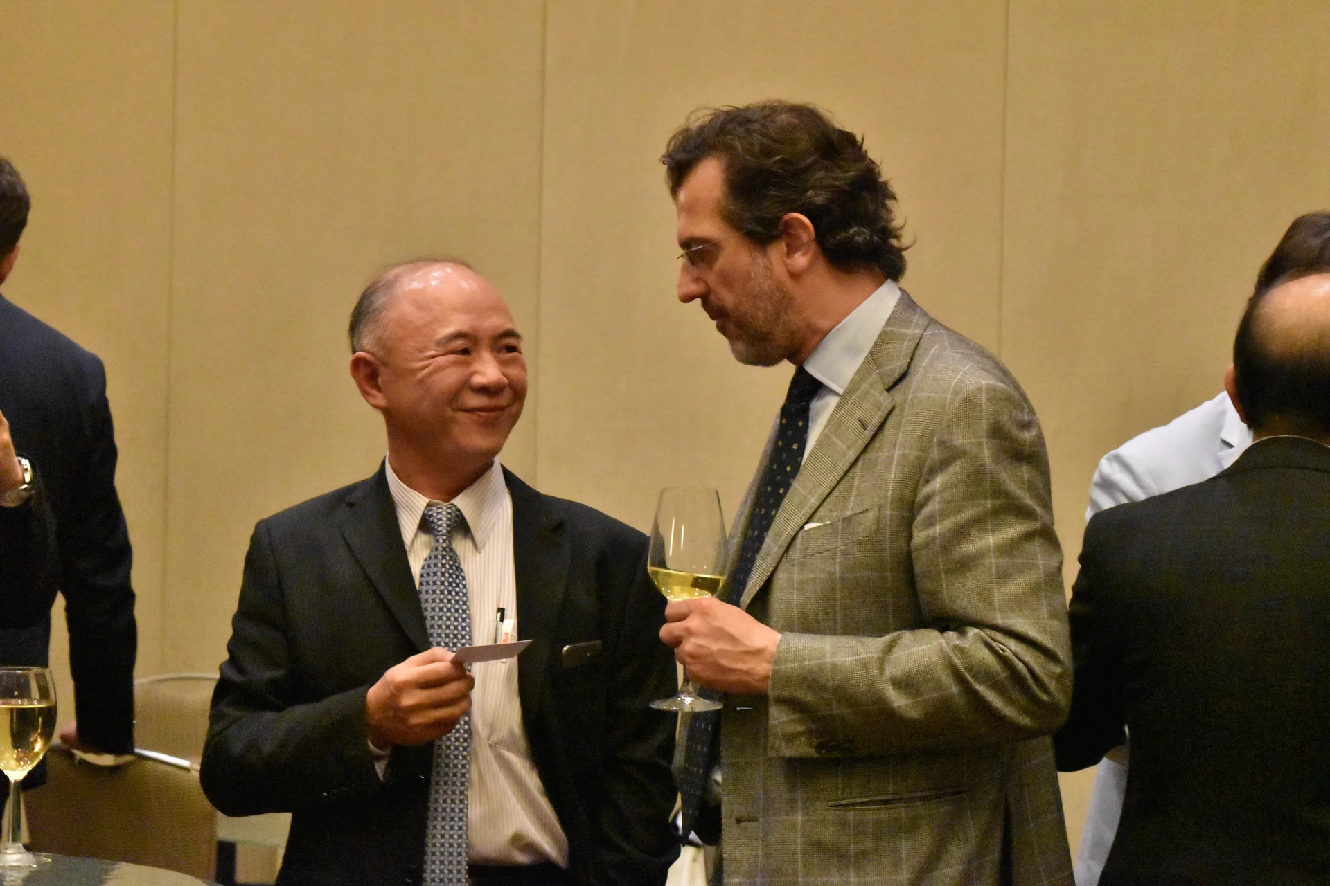 Networking Event at IFED - International Federation of Esthetic Dentistry Two professionals talking during an IFED networking event, one holding a glass of wine and the other a business card.